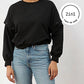 Cropped Sweater in schwarz am Körper einer Frau mit weißem, rundem 2IN1 Icon