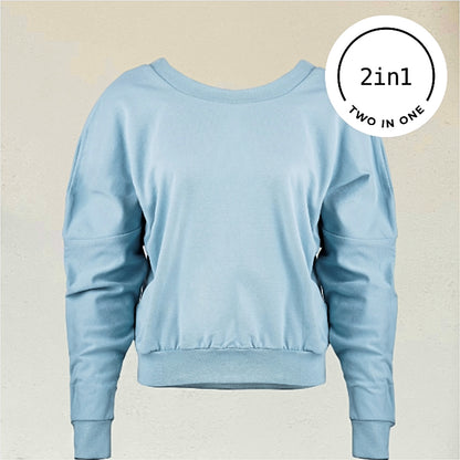 Hellblaues Sweatshirt mit Rundhalsausschnitt vor beiger Wand mit weißem rundem 2IN1-Icon