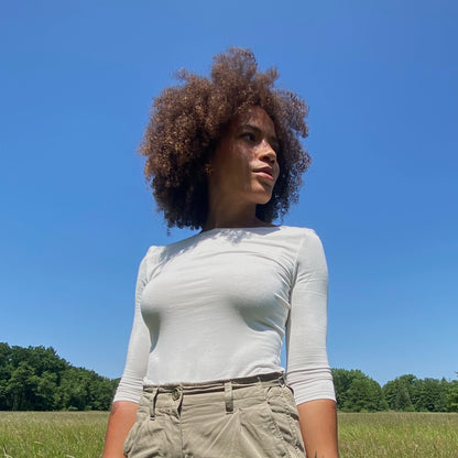 Ausschnitt von Frau mit Ballerina T in ecru stehend in Wiese vor blauem Himmel