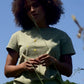 Frau mit Sagefarbenem T-Shirt vor blauem Himmel