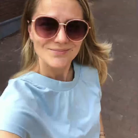 Gesicht einer Frau mit runder Sonnenbrille und hellblauem T-Shirt von schräg oben