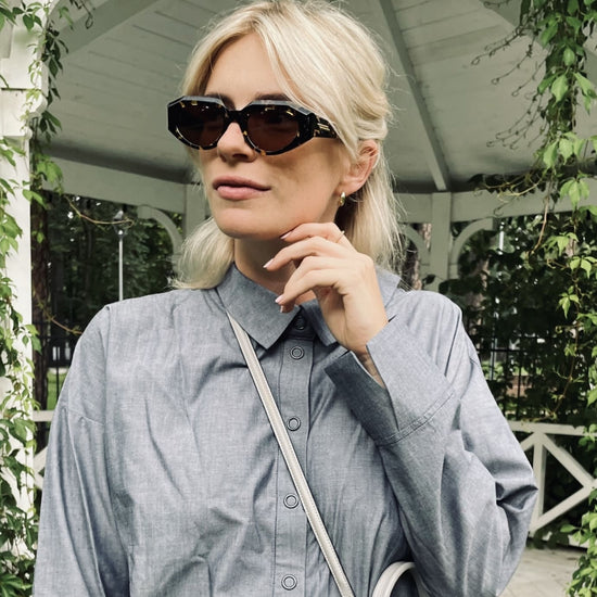 blonde Frau mit schwarzer Sonnenbrille und denimfarbenem Shirt