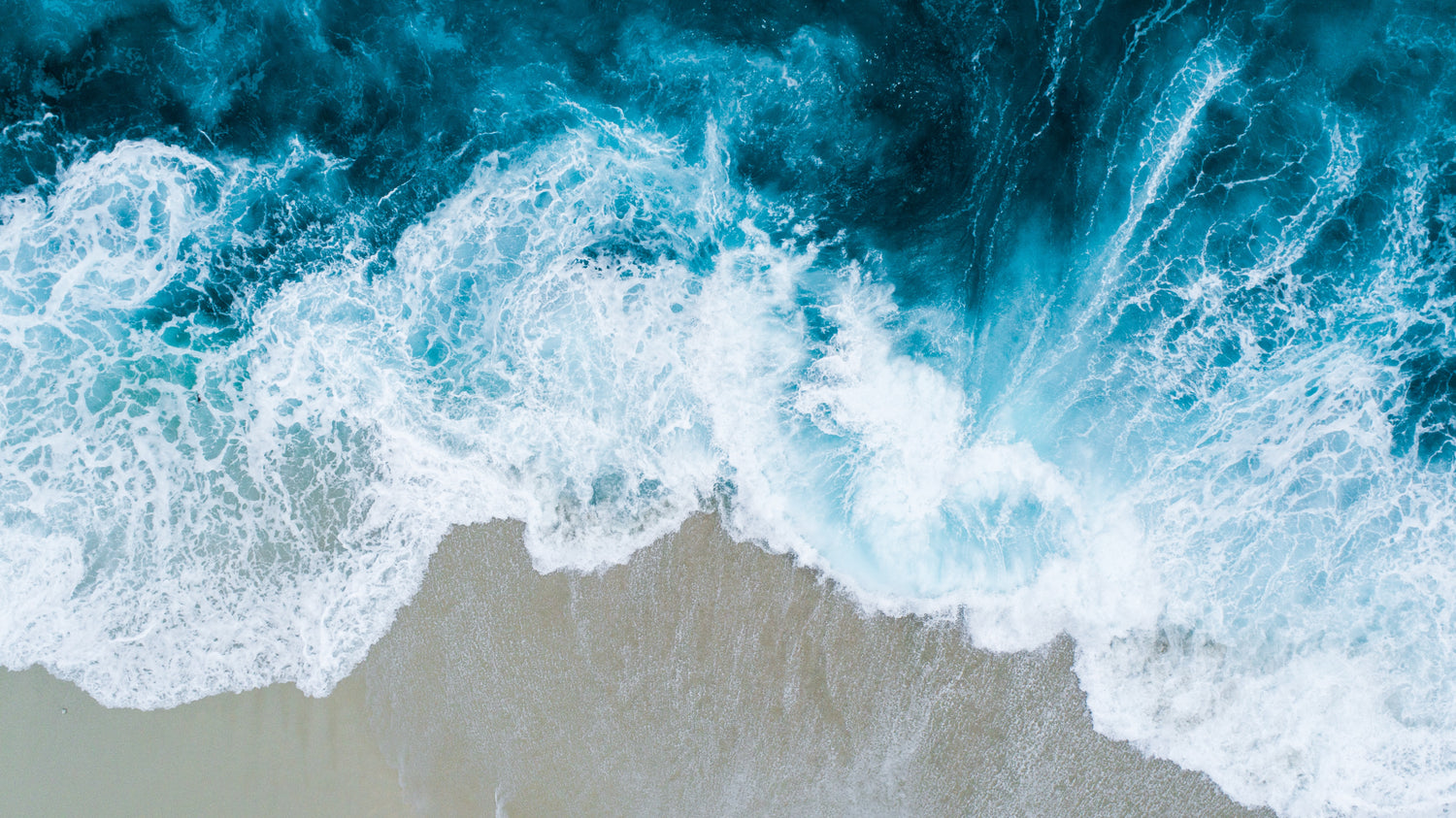 Türkiesfarbenes Meerwasser mit Strand von oben